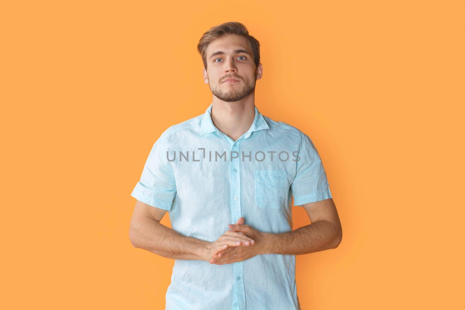 Thoughtful young man looking at camera isolated over yellow background by tsyhun