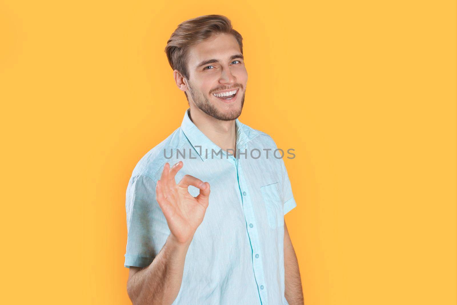 Young man showing ok isolated over yellow background by tsyhun