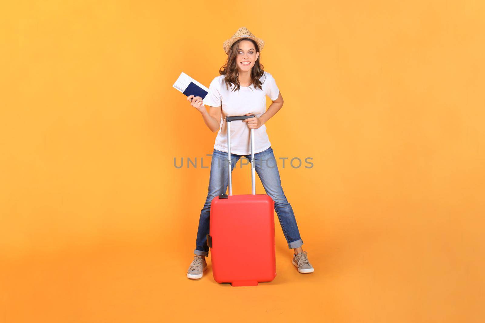 Young tourist girl in summer casual clothes, with red suitcase, passport, tickets isolated on beige background