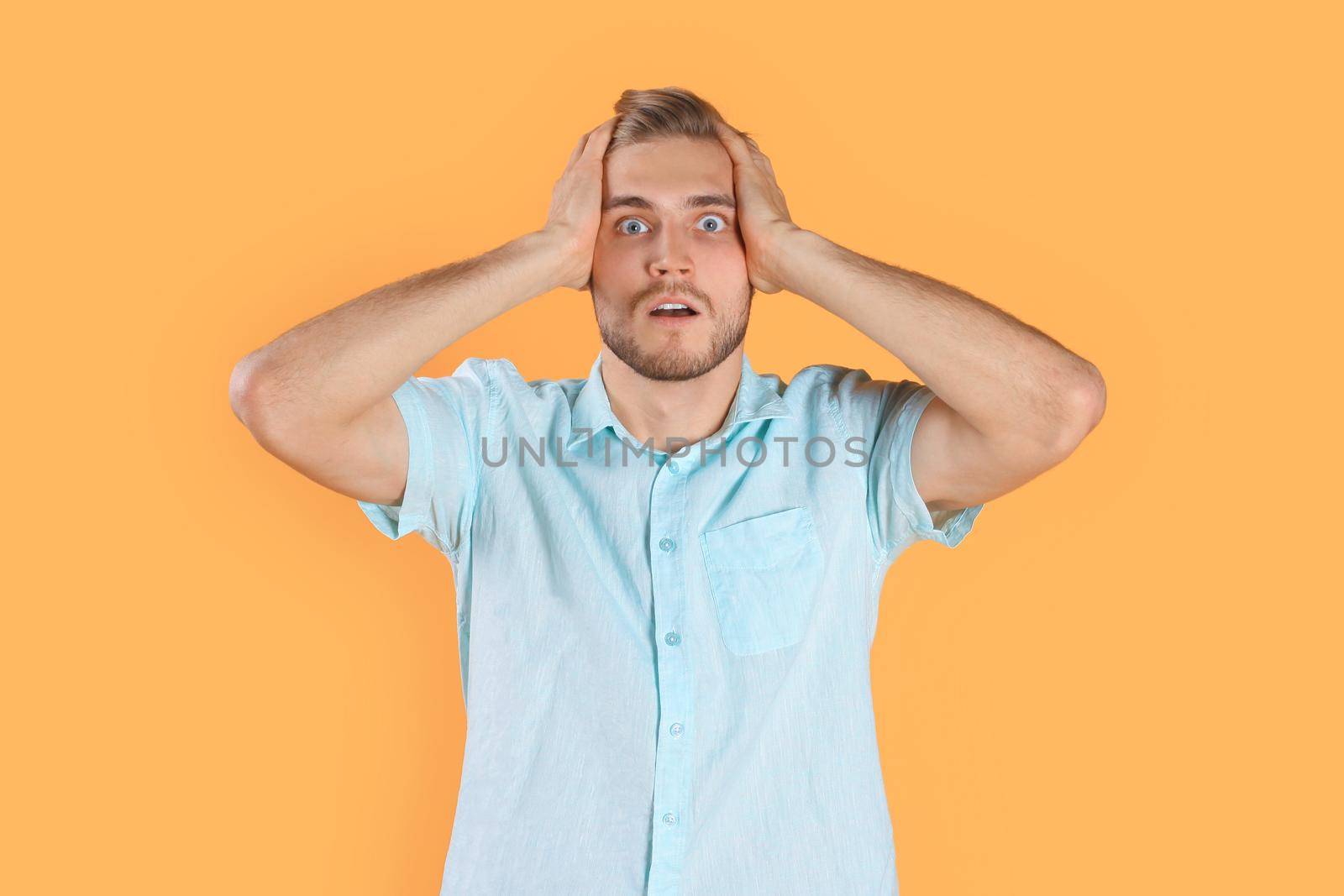 Shocked young man celebrating success isolated over yellow background by tsyhun