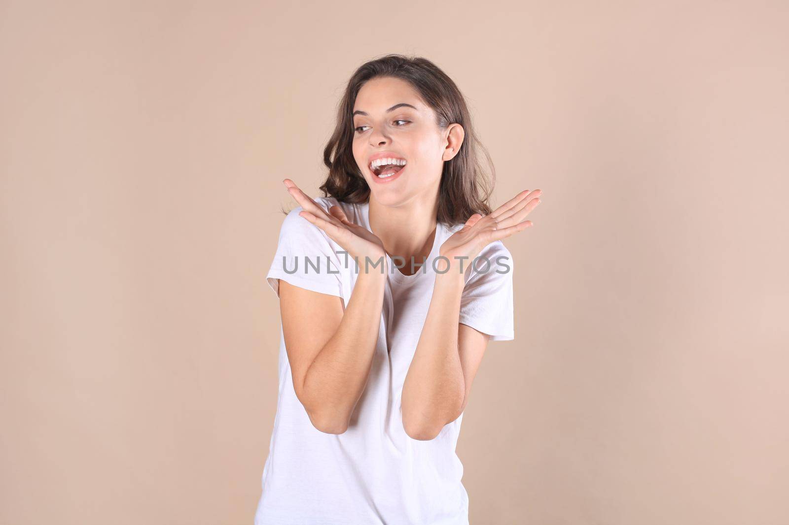 Young woman in casual clothing wondering and screaming isolated over beige background by tsyhun