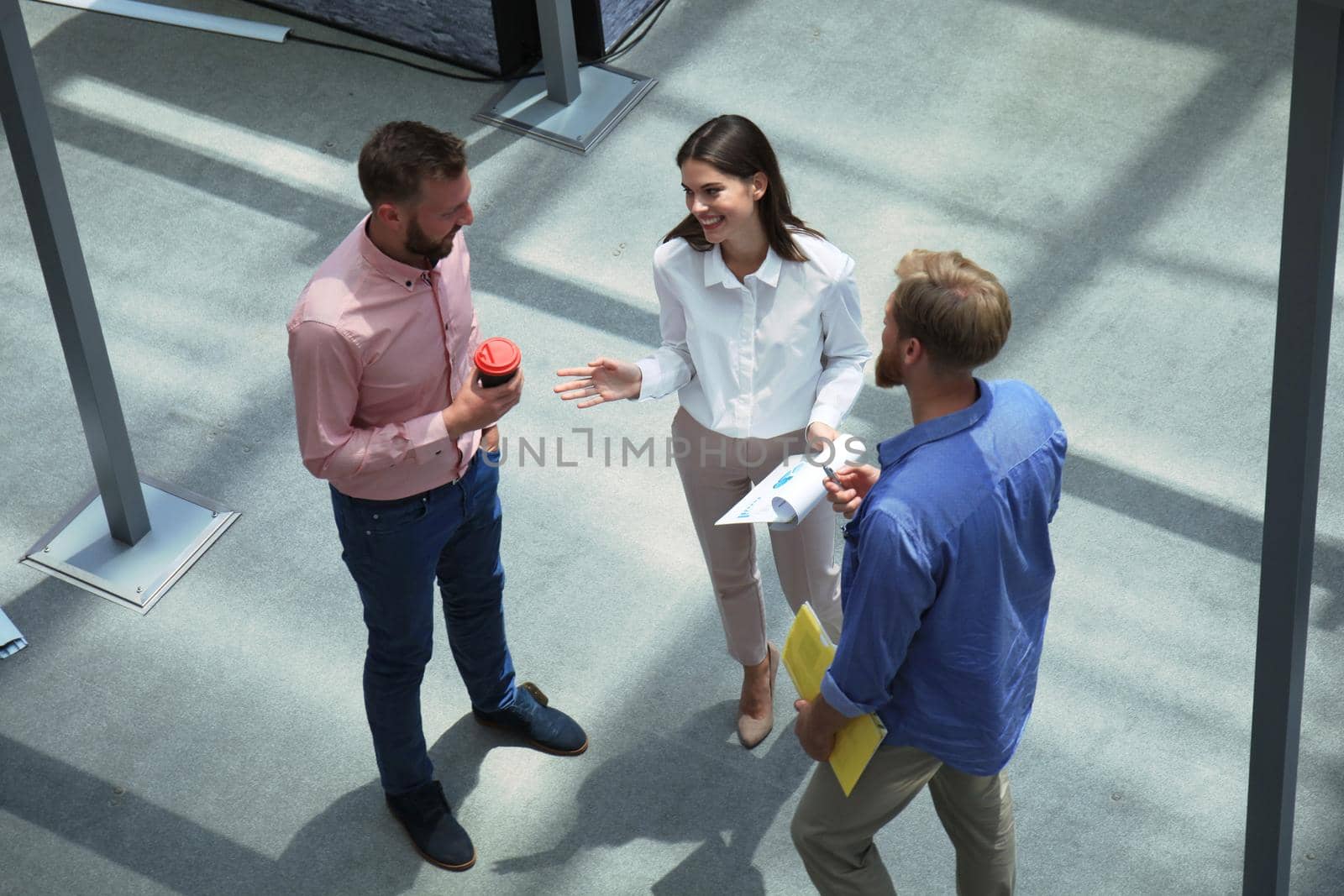 Top view of young modern people in smart casual wear discussing business while standing in creative office