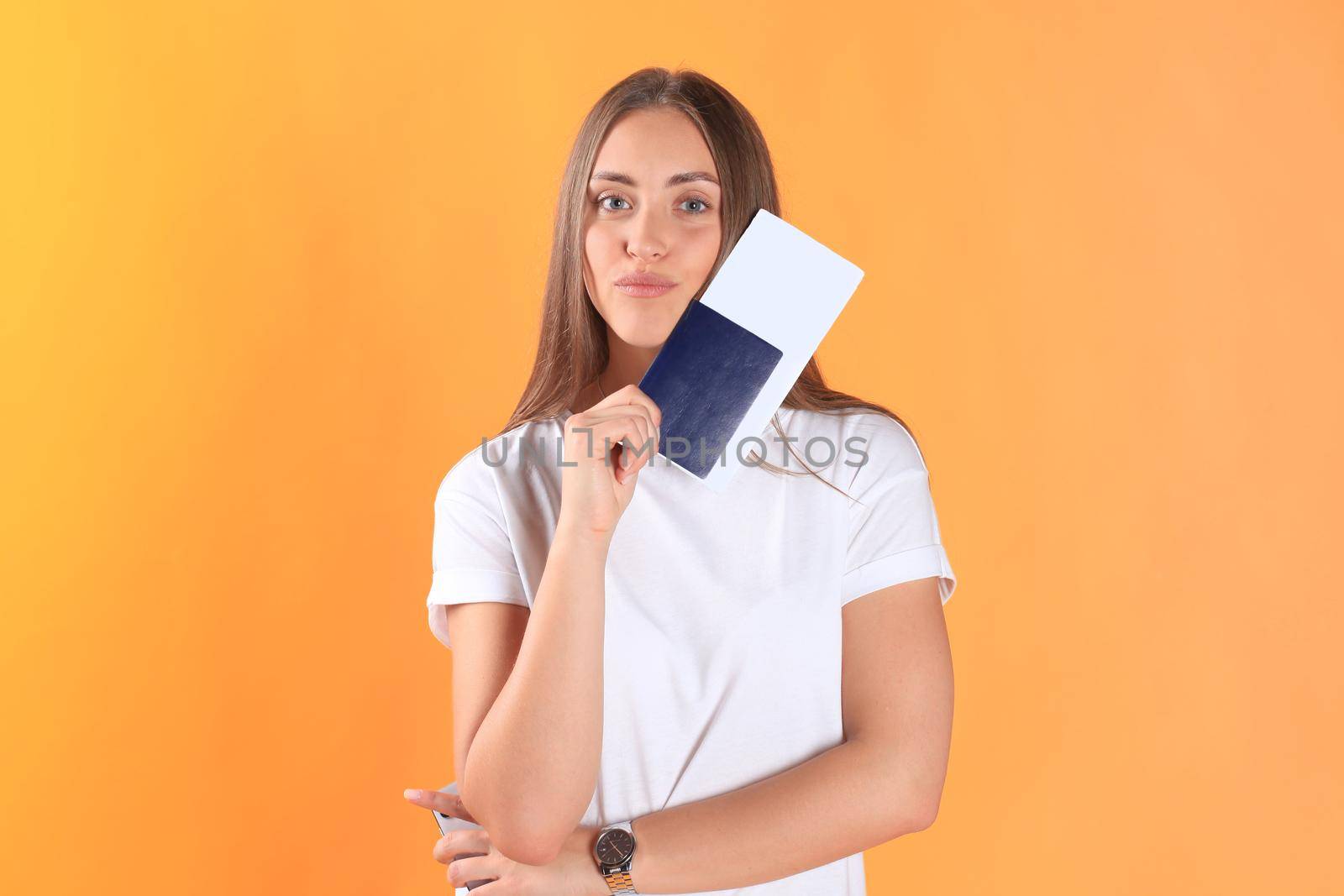 Excited young woman tourist standing isolated on yellow background holding passport with tickets, plastic credit card.