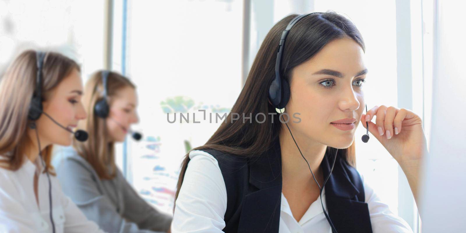 Portrait of call center worker accompanied by her team. Smiling customer support operator at work.