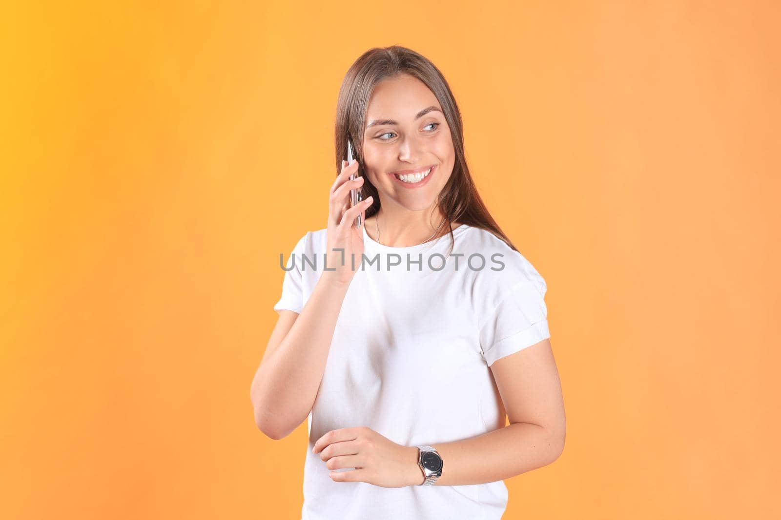 Young woman dressed in basic clothing isolated on yellow background, using mobile phone.