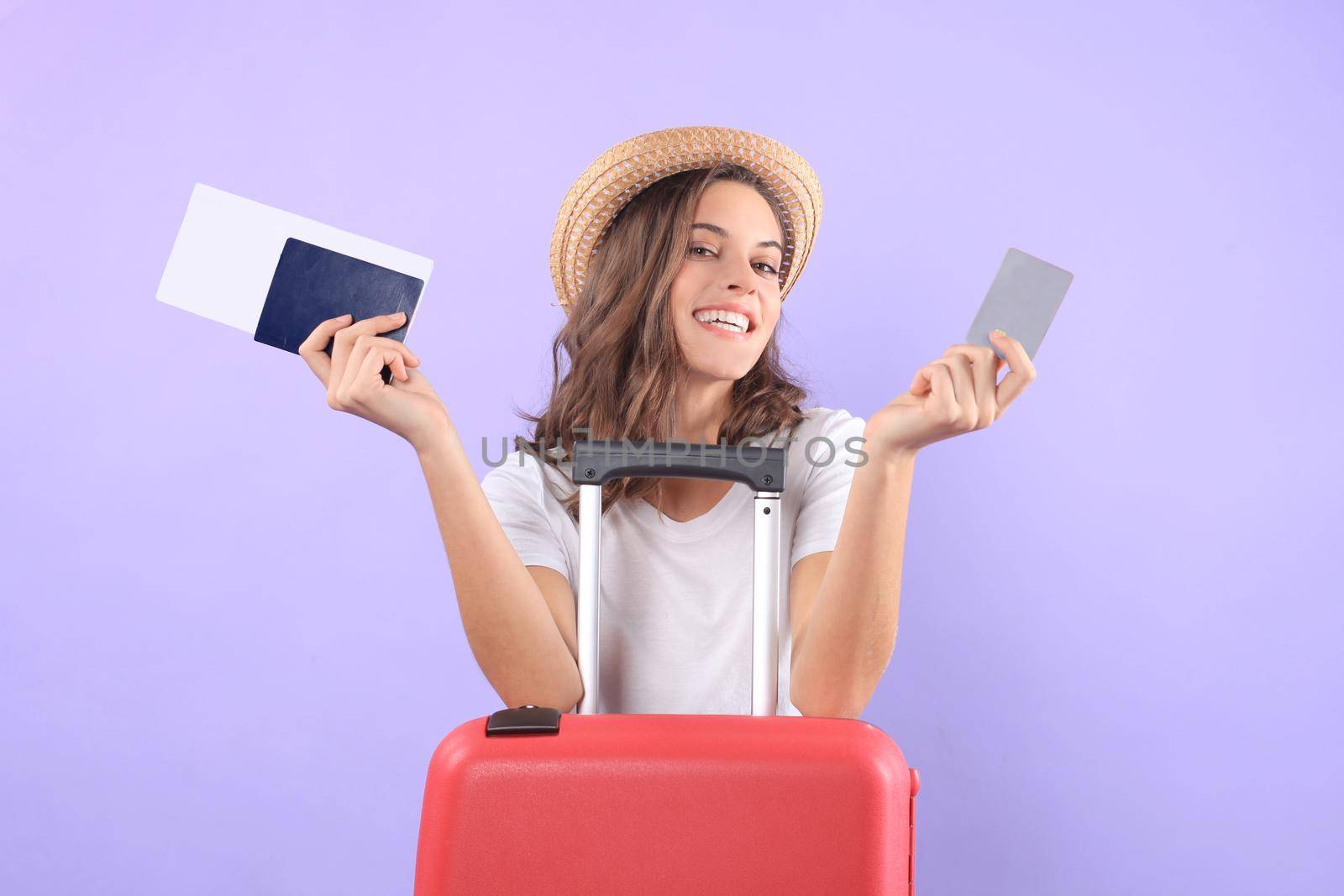 Young tourist girl in summer casual clothes, with sunglasses, red suitcase, passport isolated on purple background