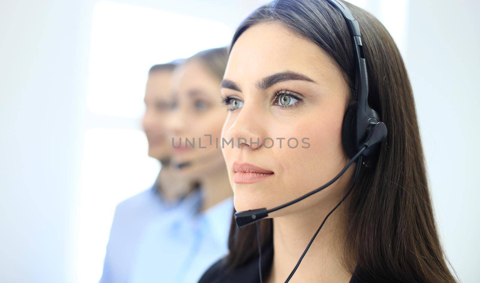 Portrait of call center worker accompanied by her team. Smiling customer support operator at work