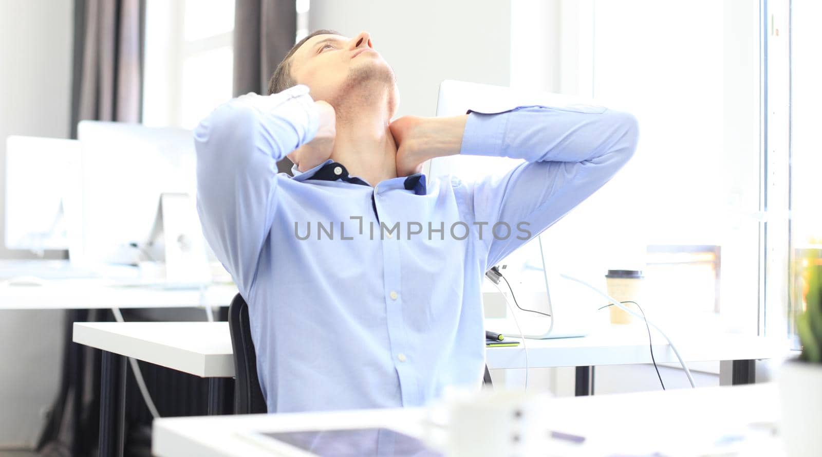 Portrait of a delighted businessman relaxing in his office by tsyhun