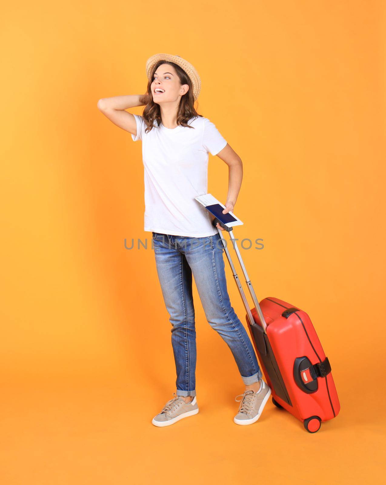 Young tourist girl in summer casual clothes, with red suitcase, passport, tickets isolated on beige background