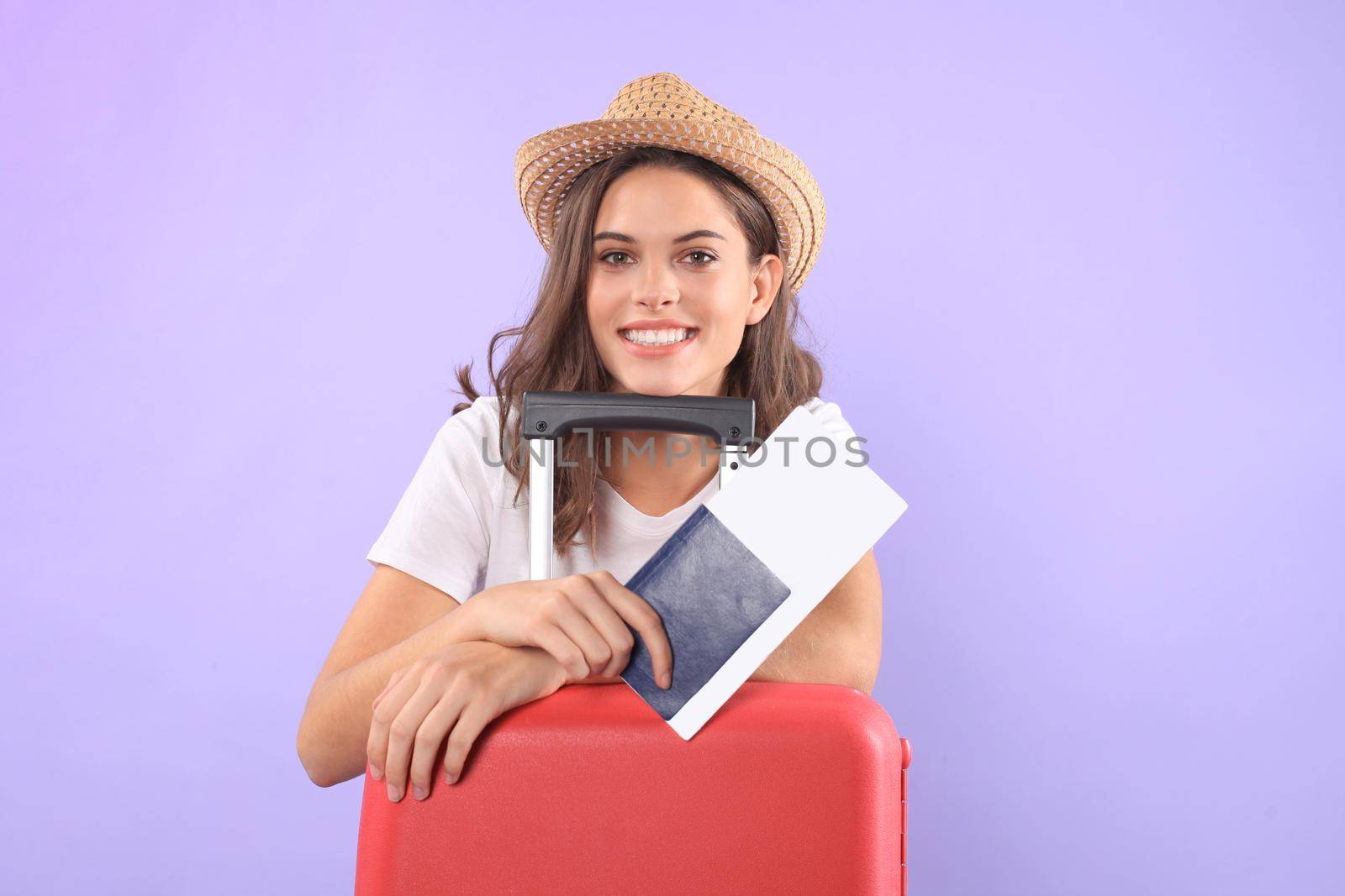 Young tourist girl in summer casual clothes, with sunglasses, red suitcase, passport isolated on purple background by tsyhun