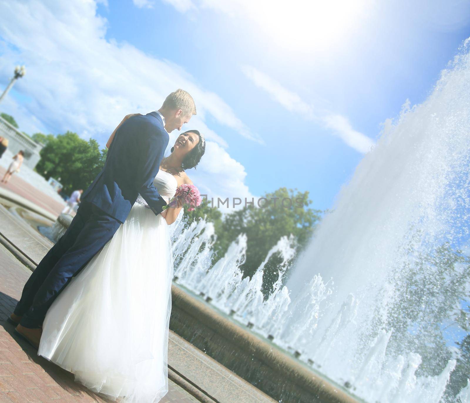 newlywed couple standing near a fountain .the concept of happiness
