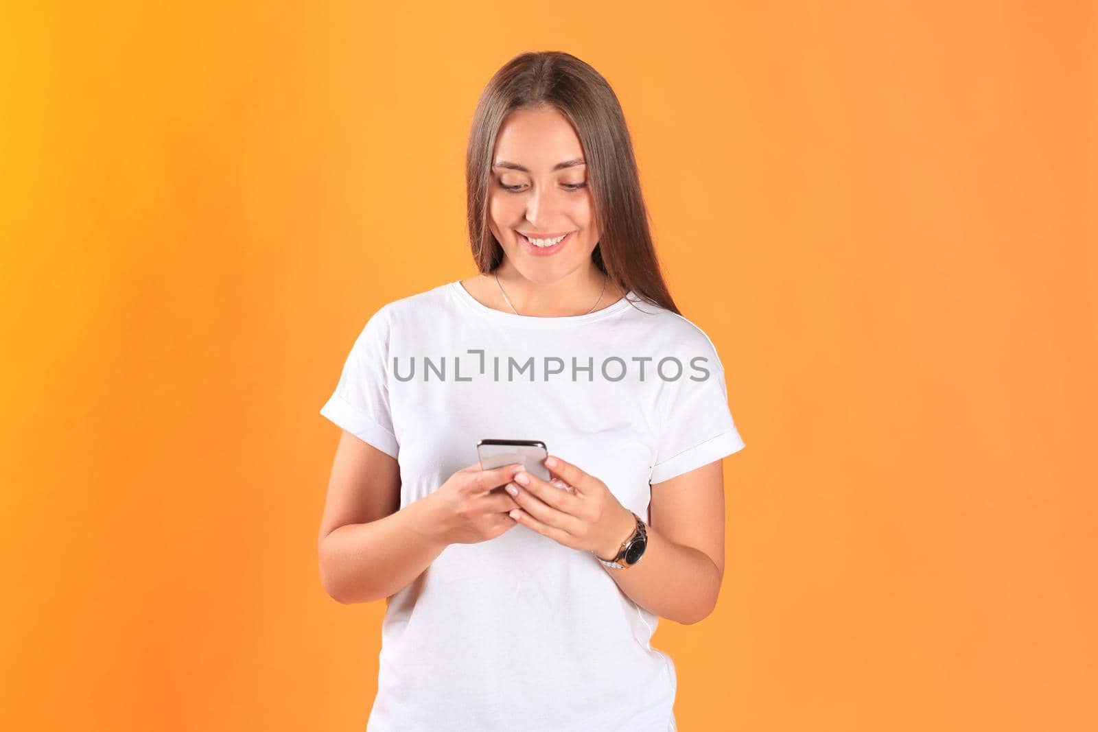 Young woman dressed in basic clothing isolated on yellow background, using mobile phone. by tsyhun