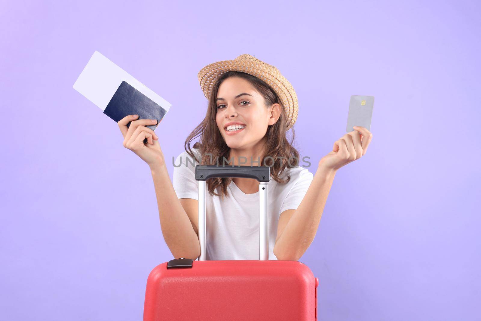 Young tourist girl in summer casual clothes, with sunglasses, red suitcase, passport isolated on purple background by tsyhun