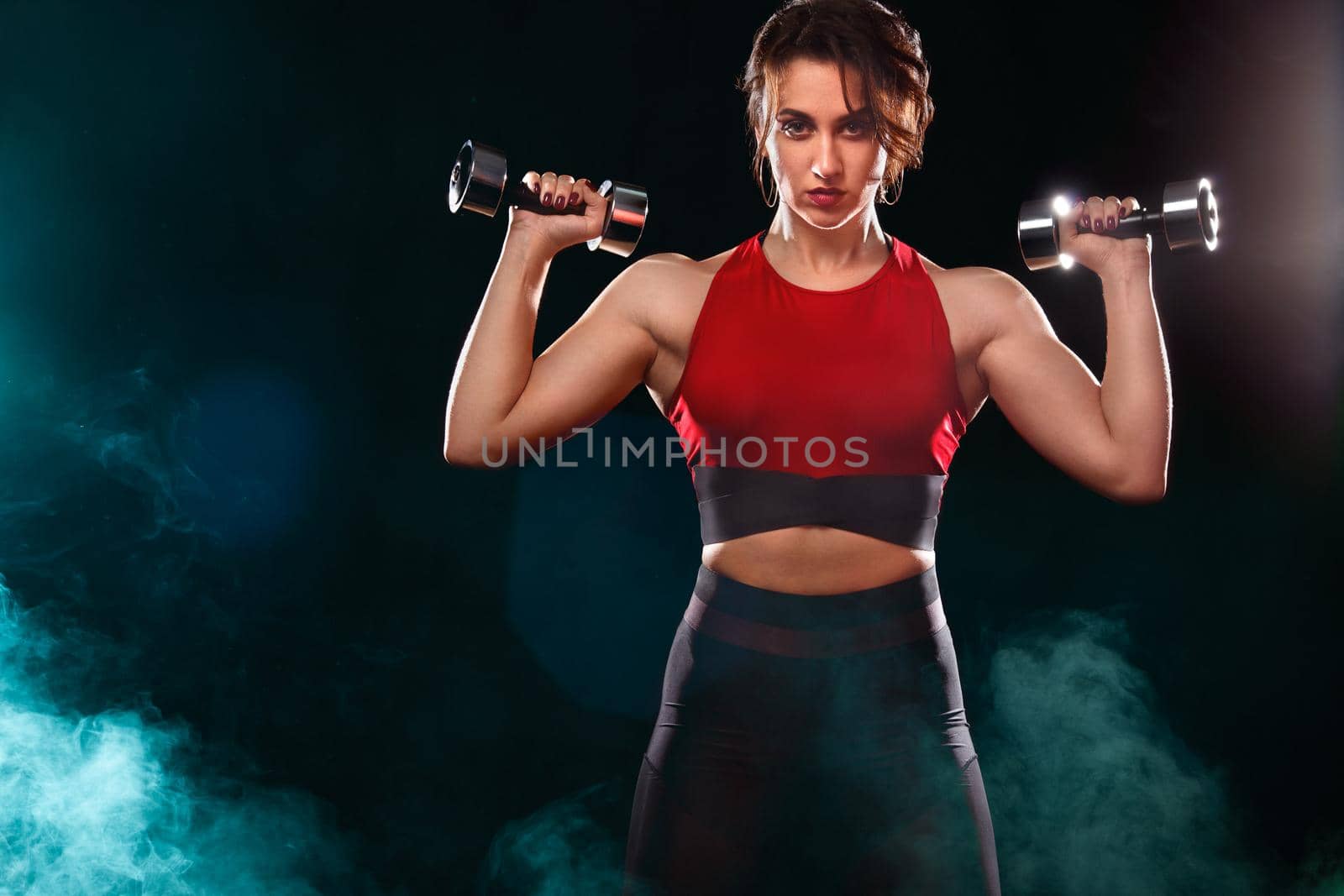 Sporty fit woman, athlete with dumbbells make fitness exercises on black background. by MikeOrlov