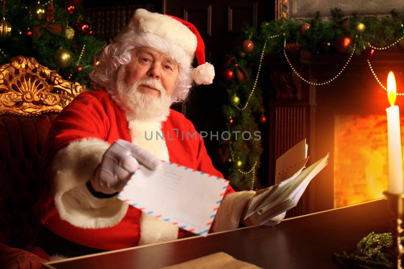 Santa sitting at the Christmas tree, holding Christmas letters and having a rest by the fireplace.