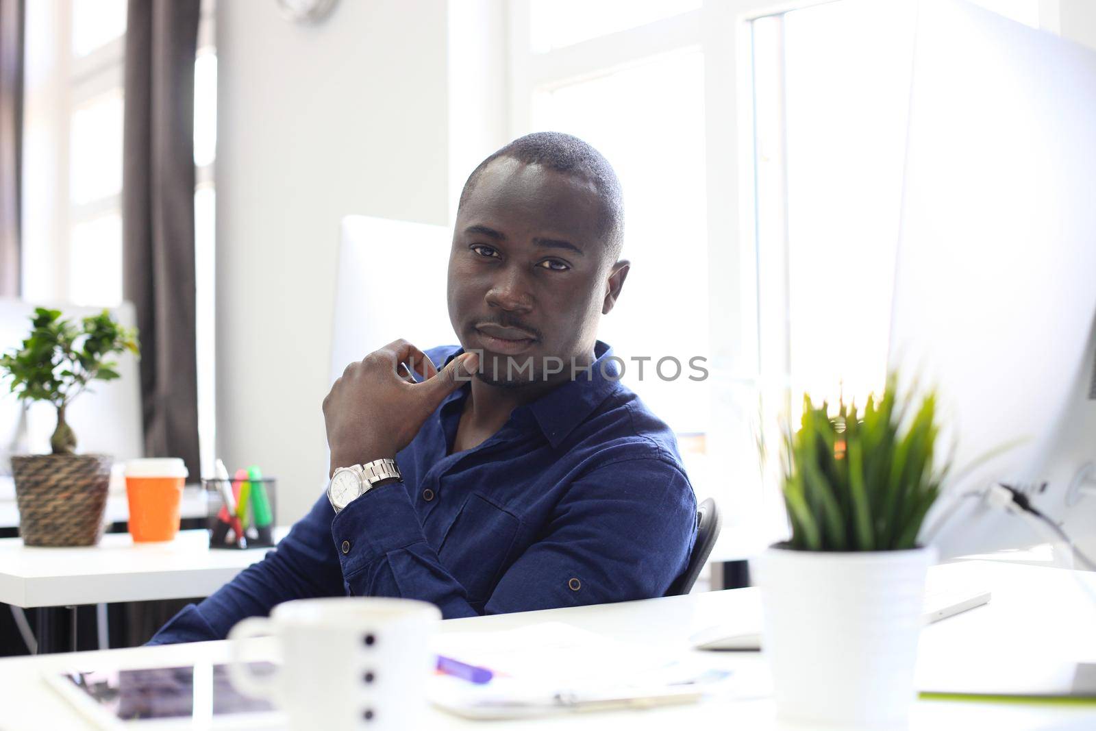 Portrait of a happy African American entrepreneur displaying computer in office by tsyhun