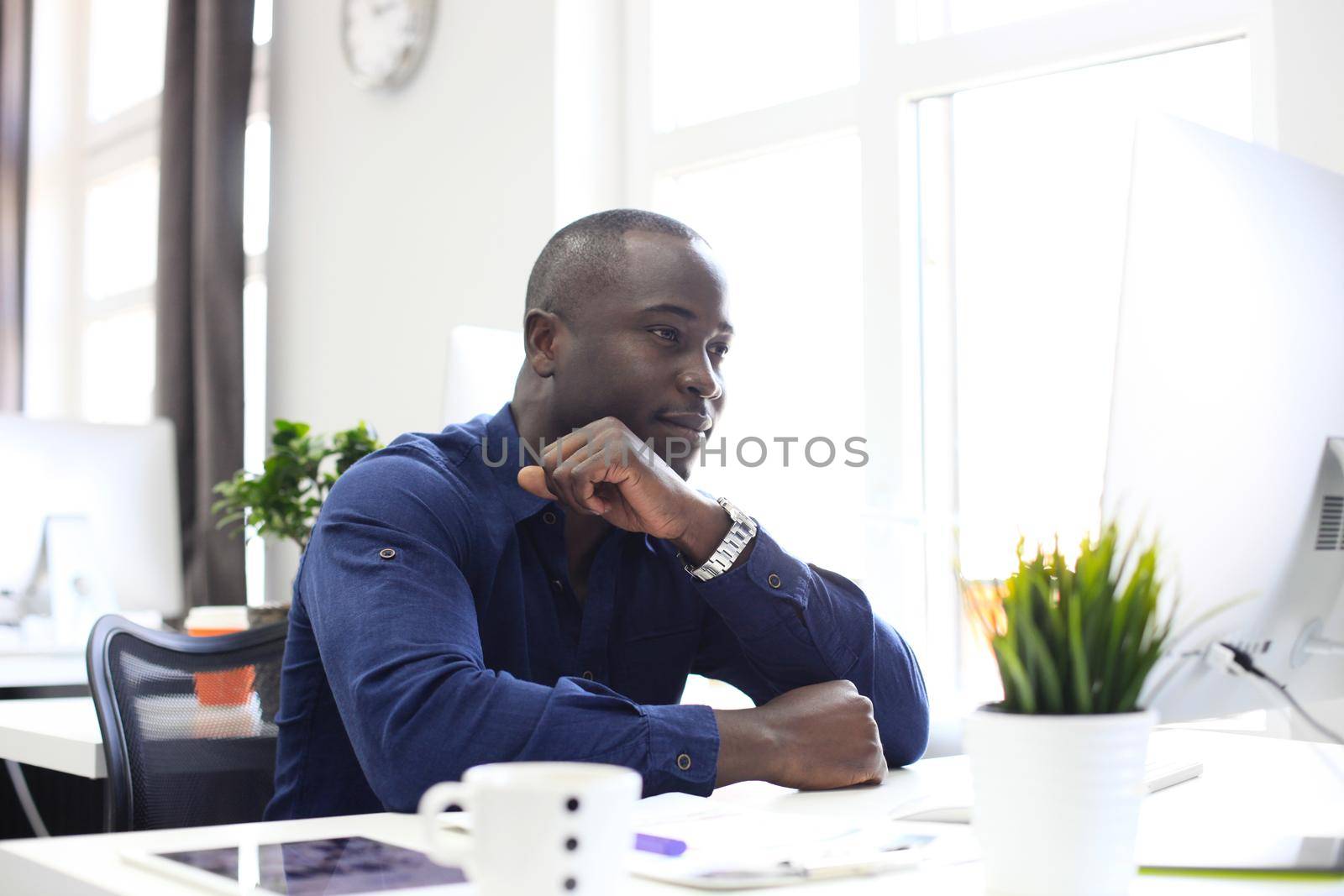 Portrait of a happy African American entrepreneur displaying computer in office by tsyhun