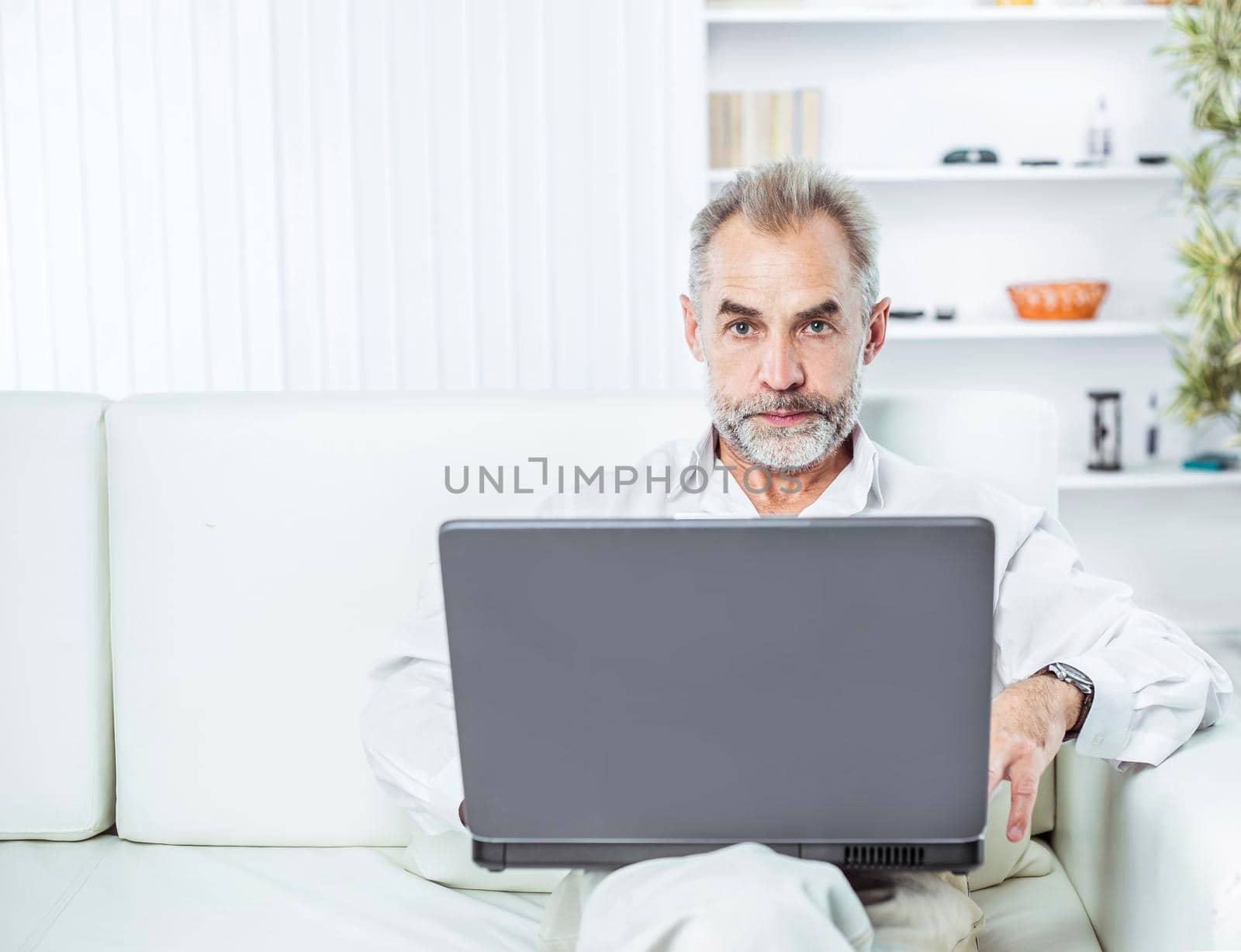 businessman working on laptop sitting on sofa in modern office.