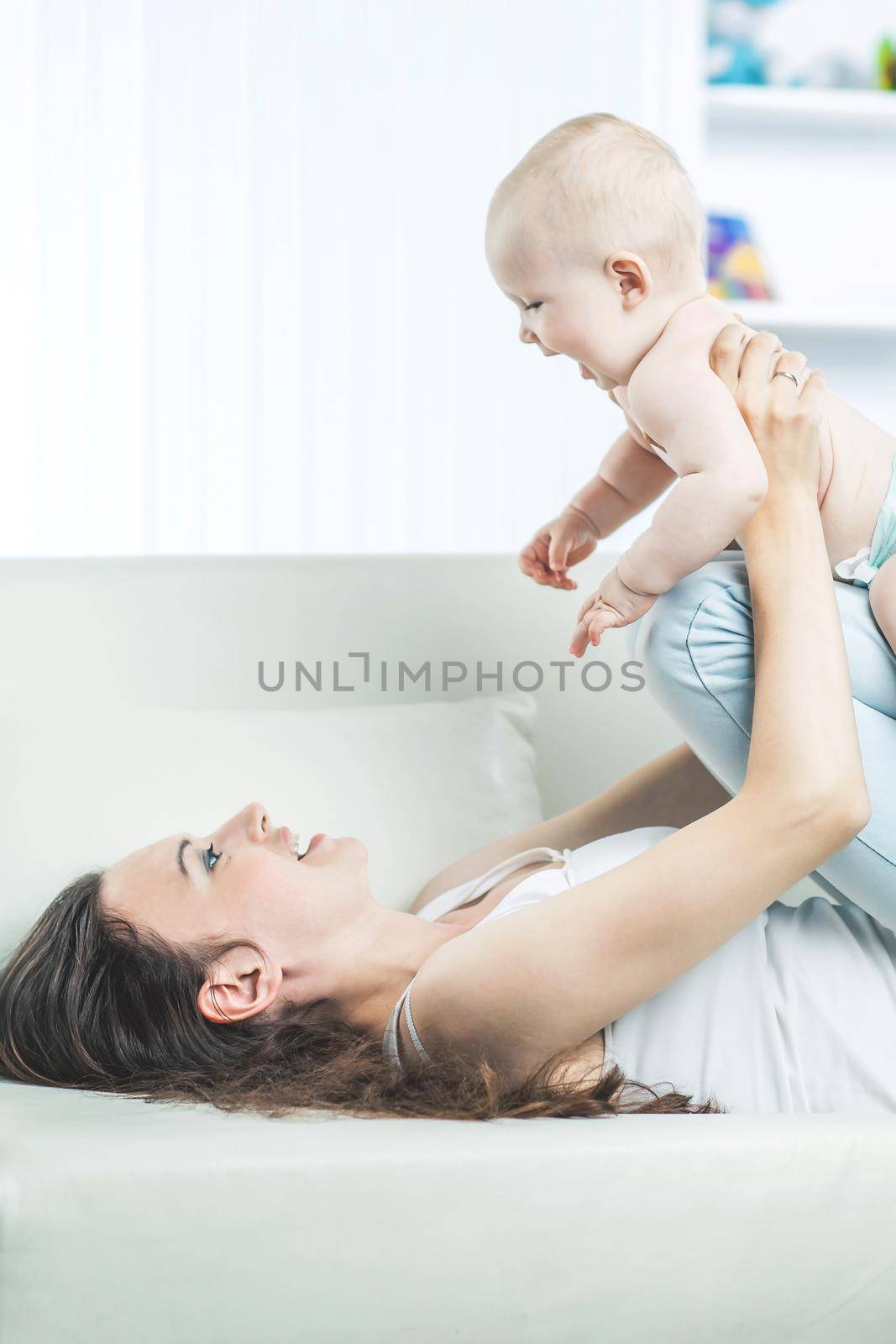 concept of motherhood:happy mother playing with one year old baby in the room for children by SmartPhotoLab