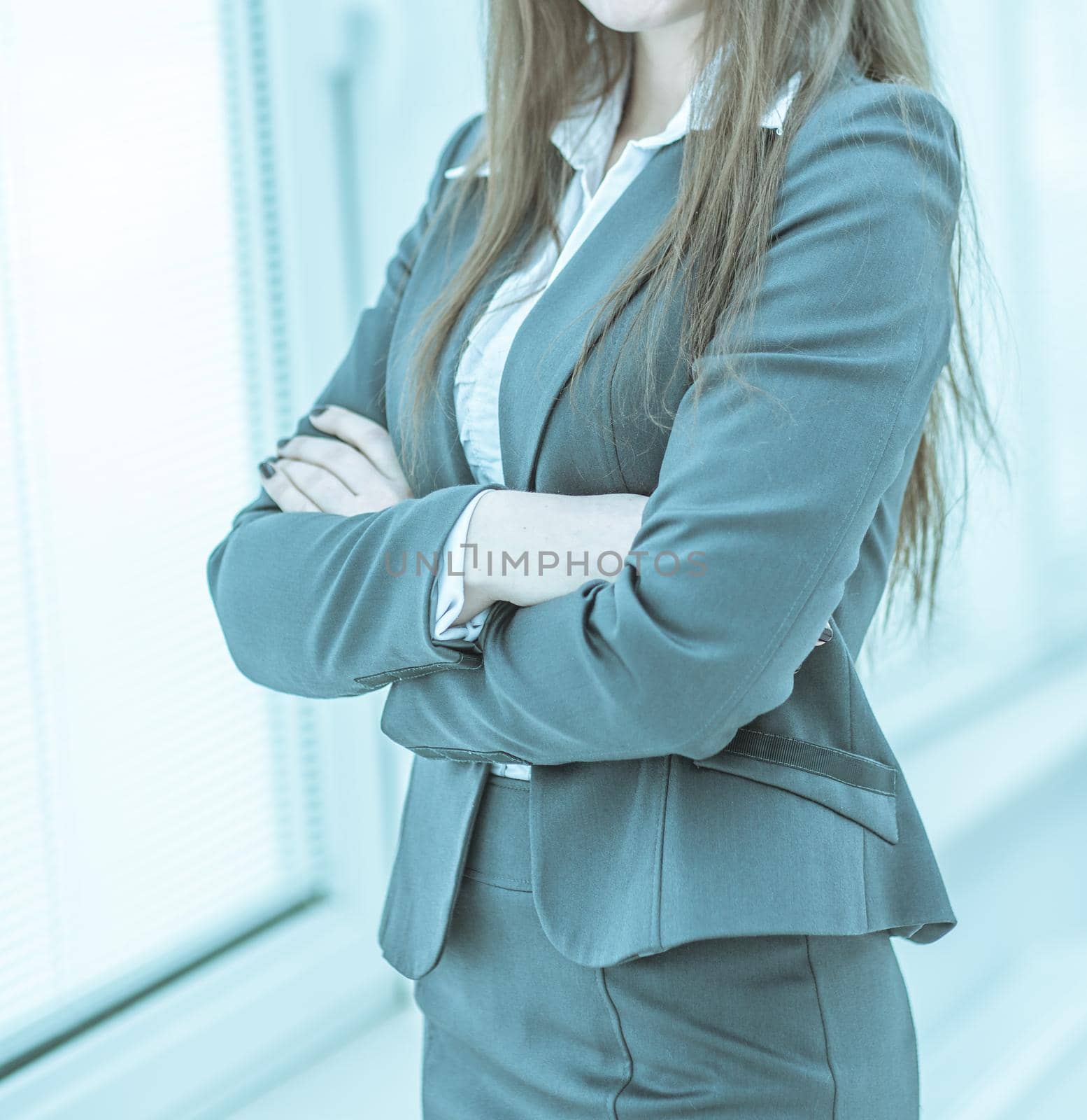 successful business woman standing near window with hands claspe by SmartPhotoLab