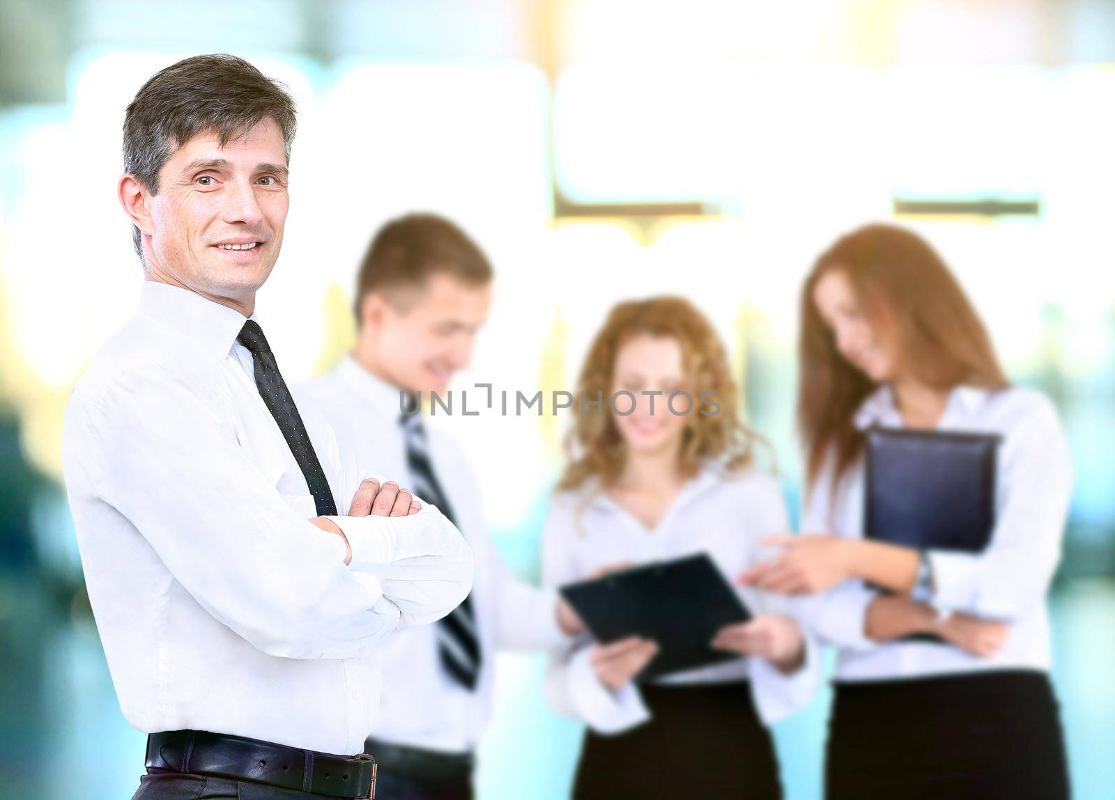 Successful business man standing with his staff in background at office