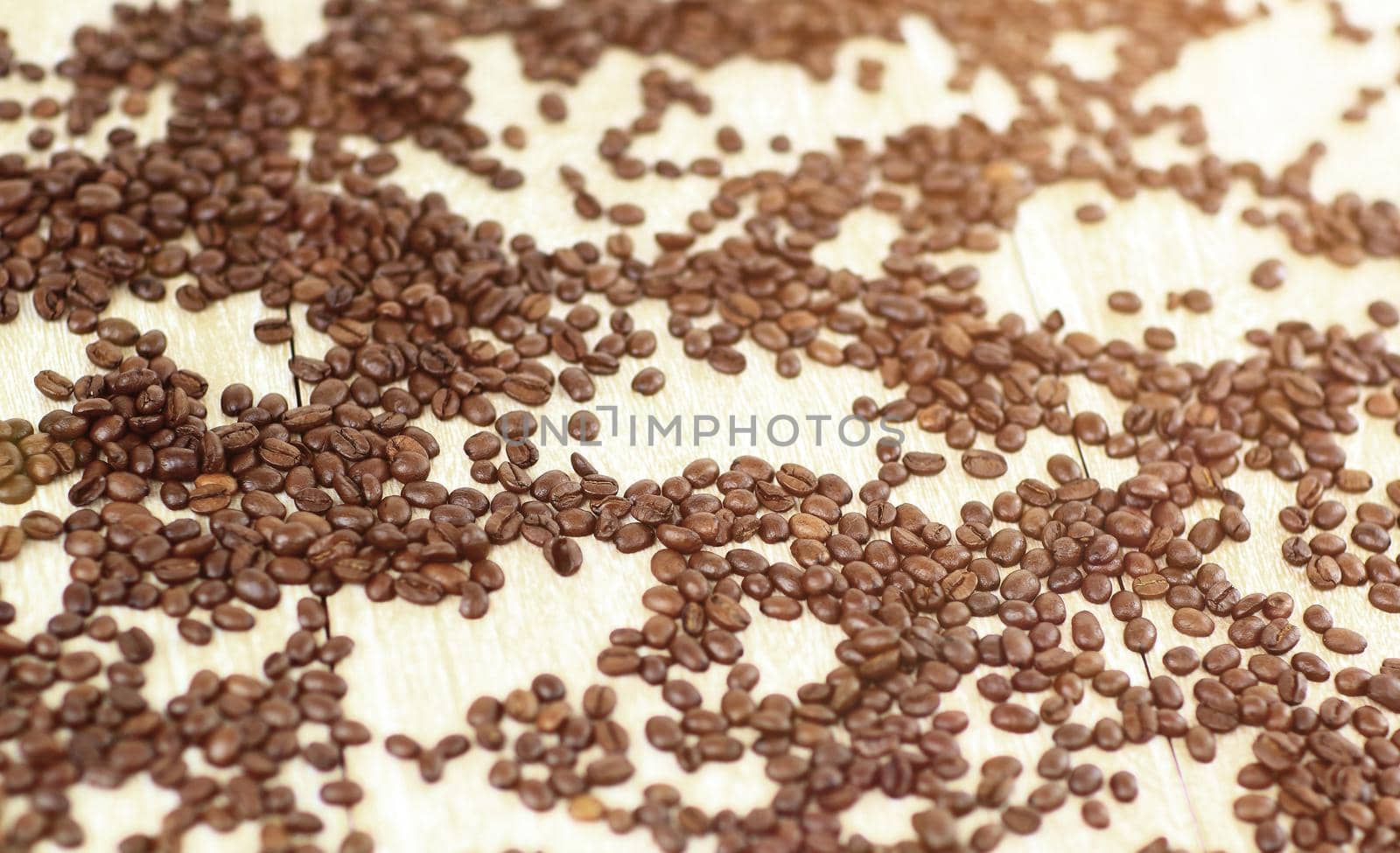 close-up of black coffee beans scattered on a wooden table.background.