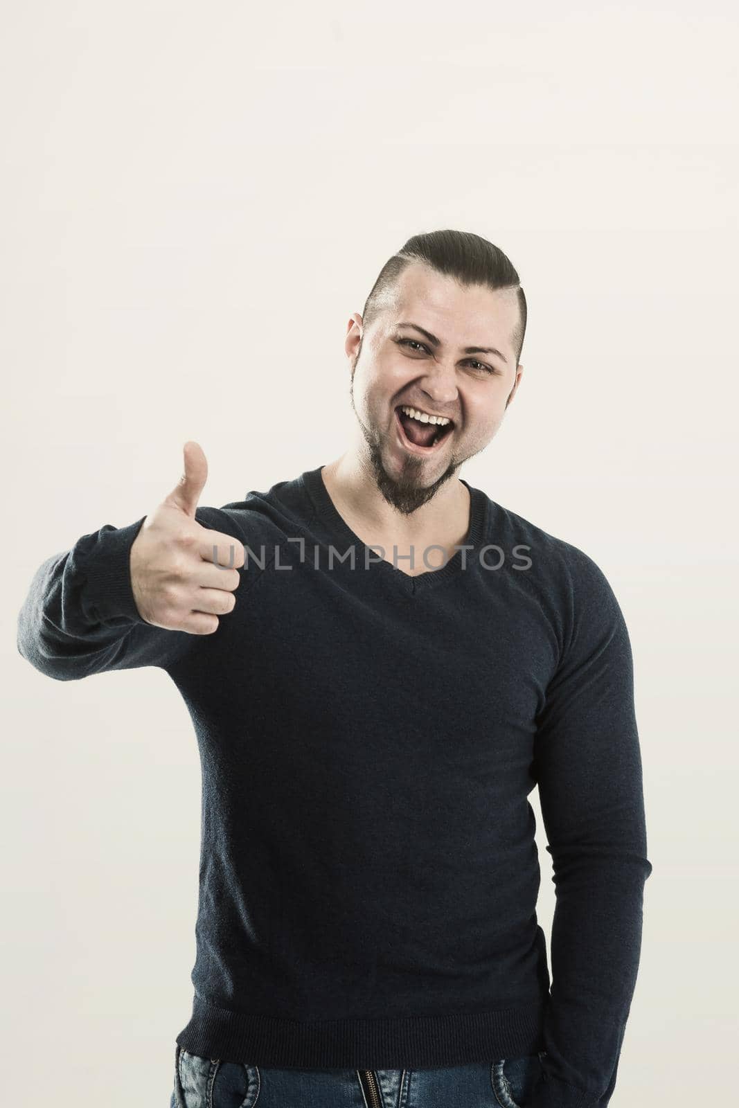 athletic guy bodybuilder in jeans and t-shirt showing gesture thumb up. the photo has a empty space for your text
