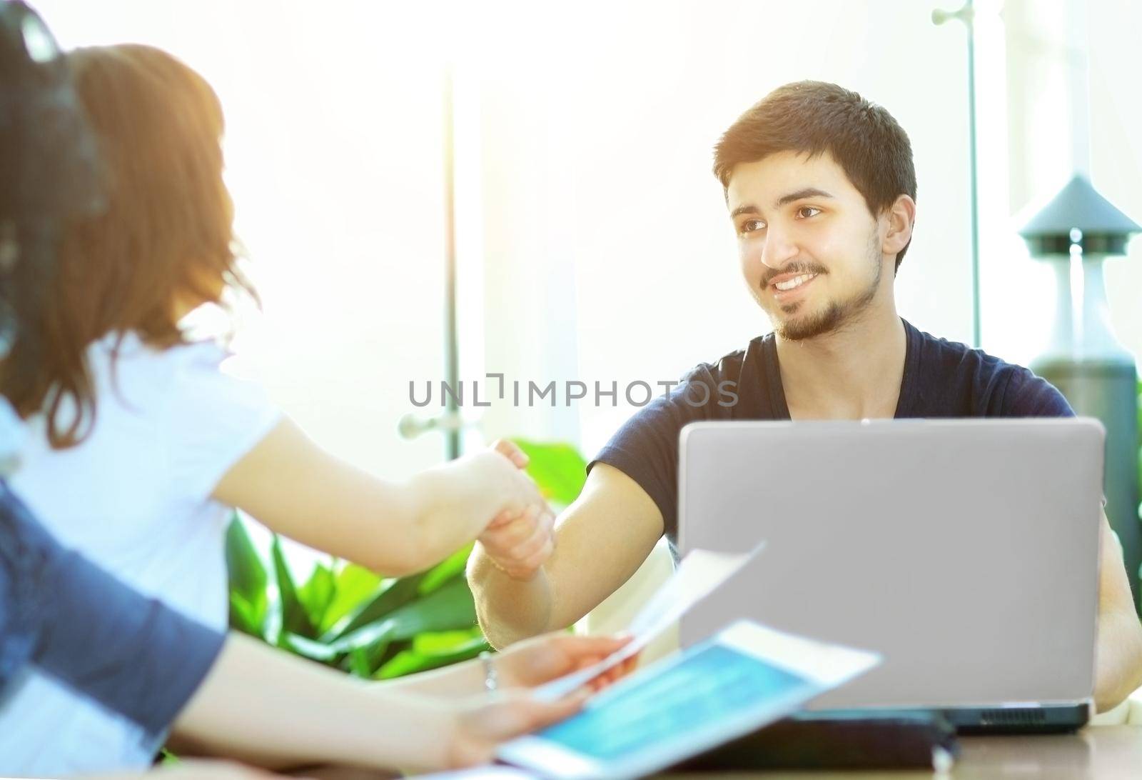 close up.Manager shaking hands with client sitting at his Desk by SmartPhotoLab