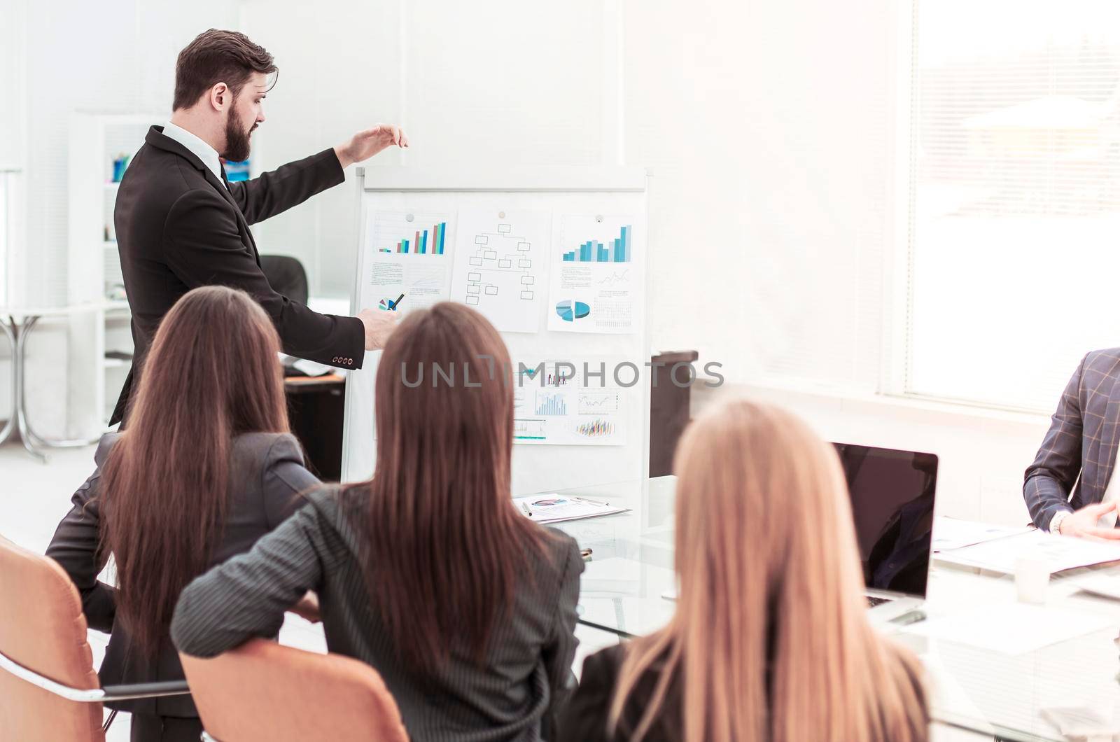 businessman pointing with a marker on the Board with the financial schedules and business team sitting on workplace