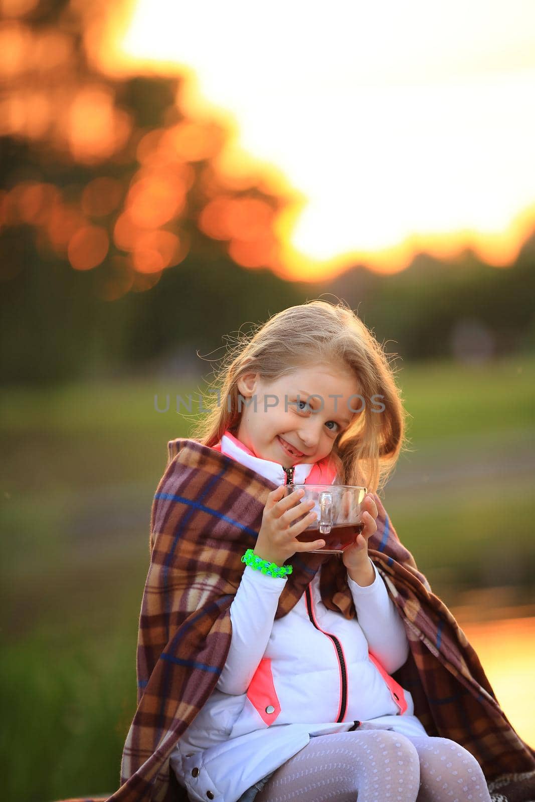 girl with a Cup of hot cocoa wrapped in a blanket sitting on a bench in the cool autumn day.the photo has a space for your text