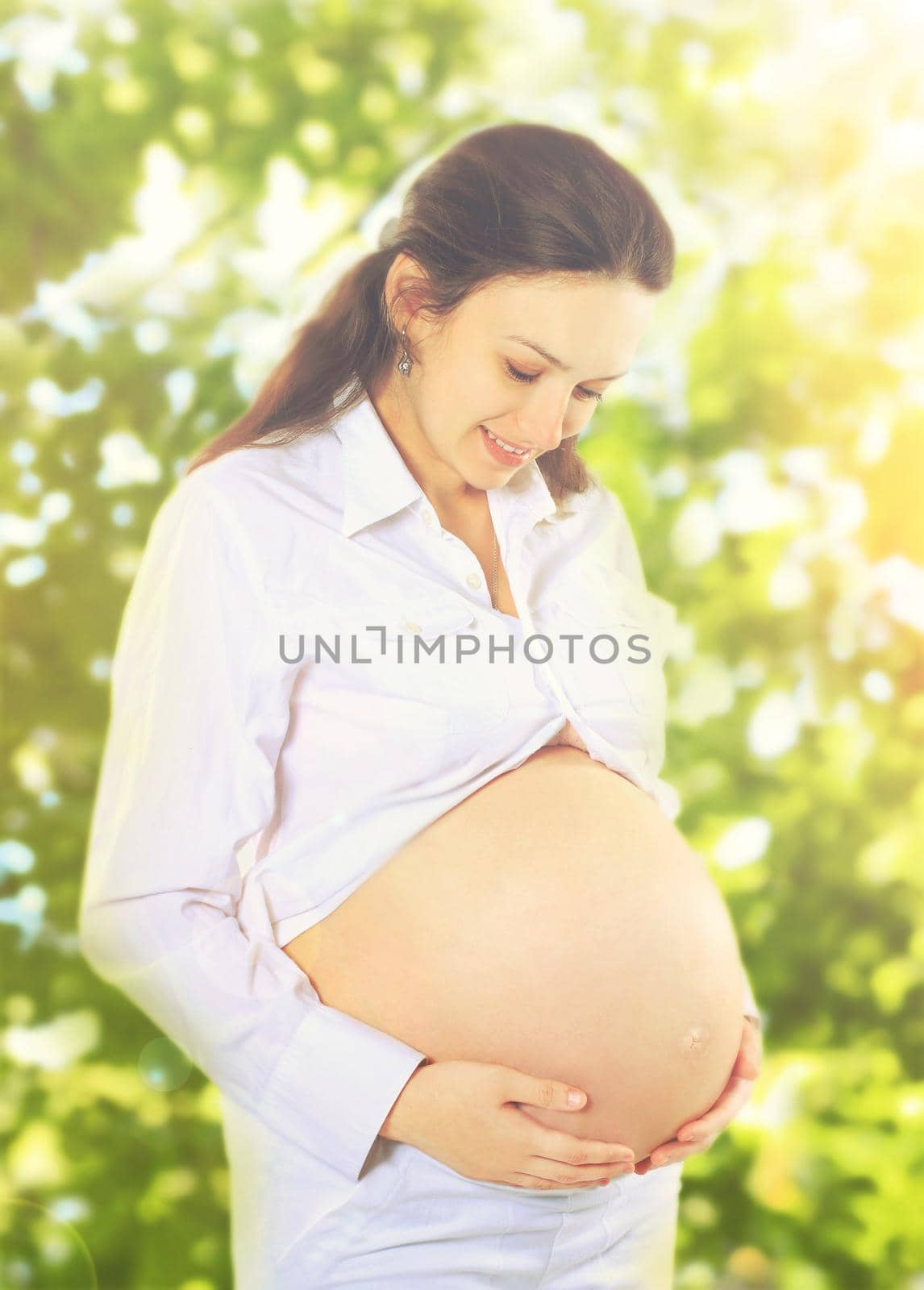 young pregnant woman looks at her belly.photo outdoors.