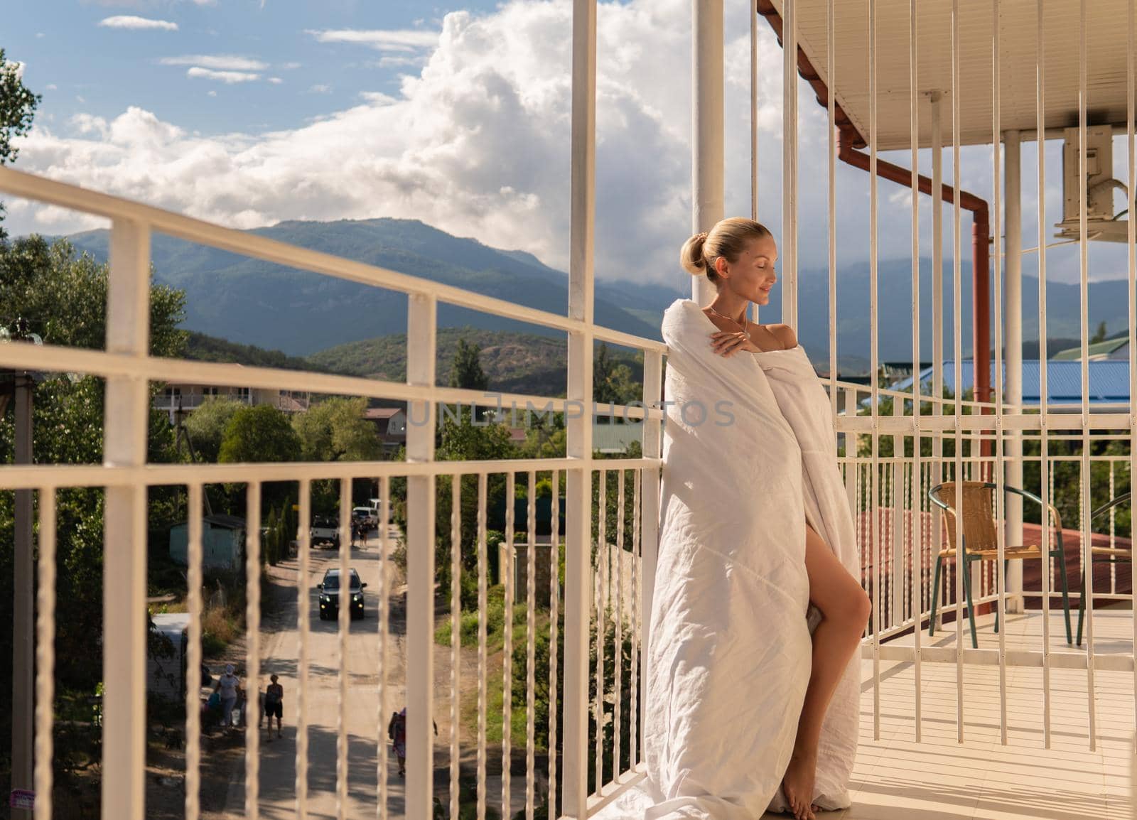 The girl sits on the balcony of the mountains and the blue sky on the background of beauty balcony caucasian lifestyle, young outdoor relax outside relaxation, morning travel. Rich lady, romantic hotel