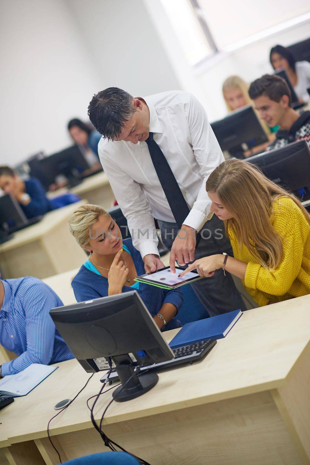 group of students with teacher in computer lab classrom learrning lessons,  get help and support