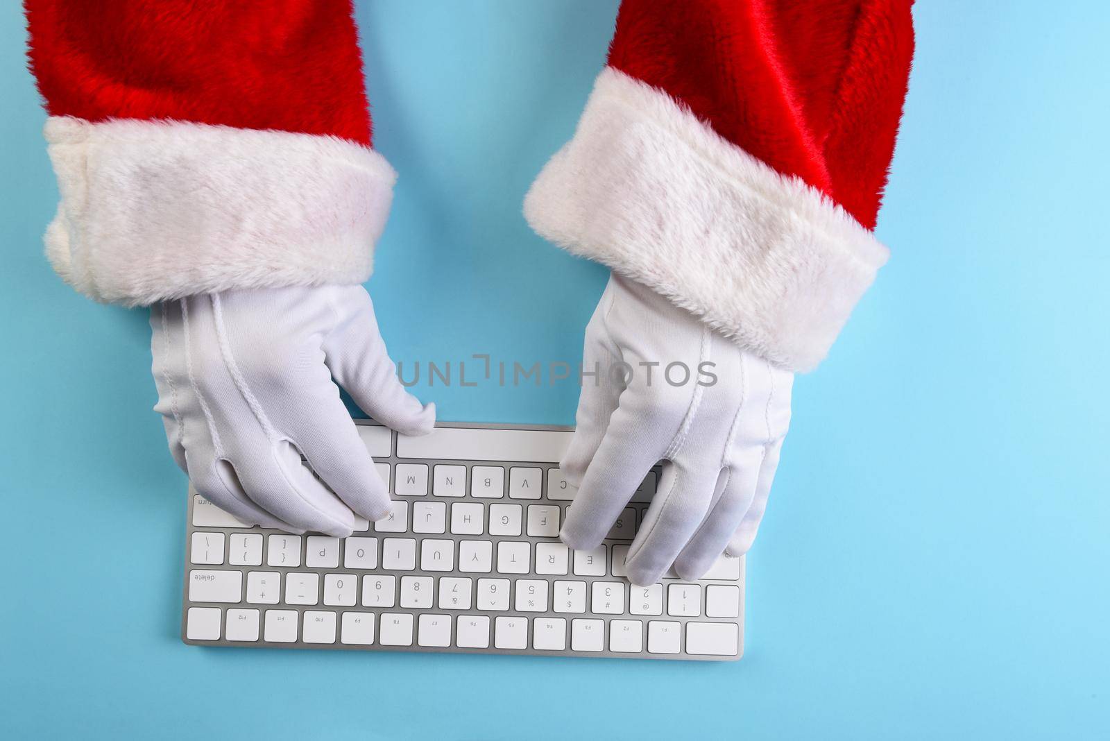High angle closeup of Santa Claus hands using his computer keyboard. by sCukrov