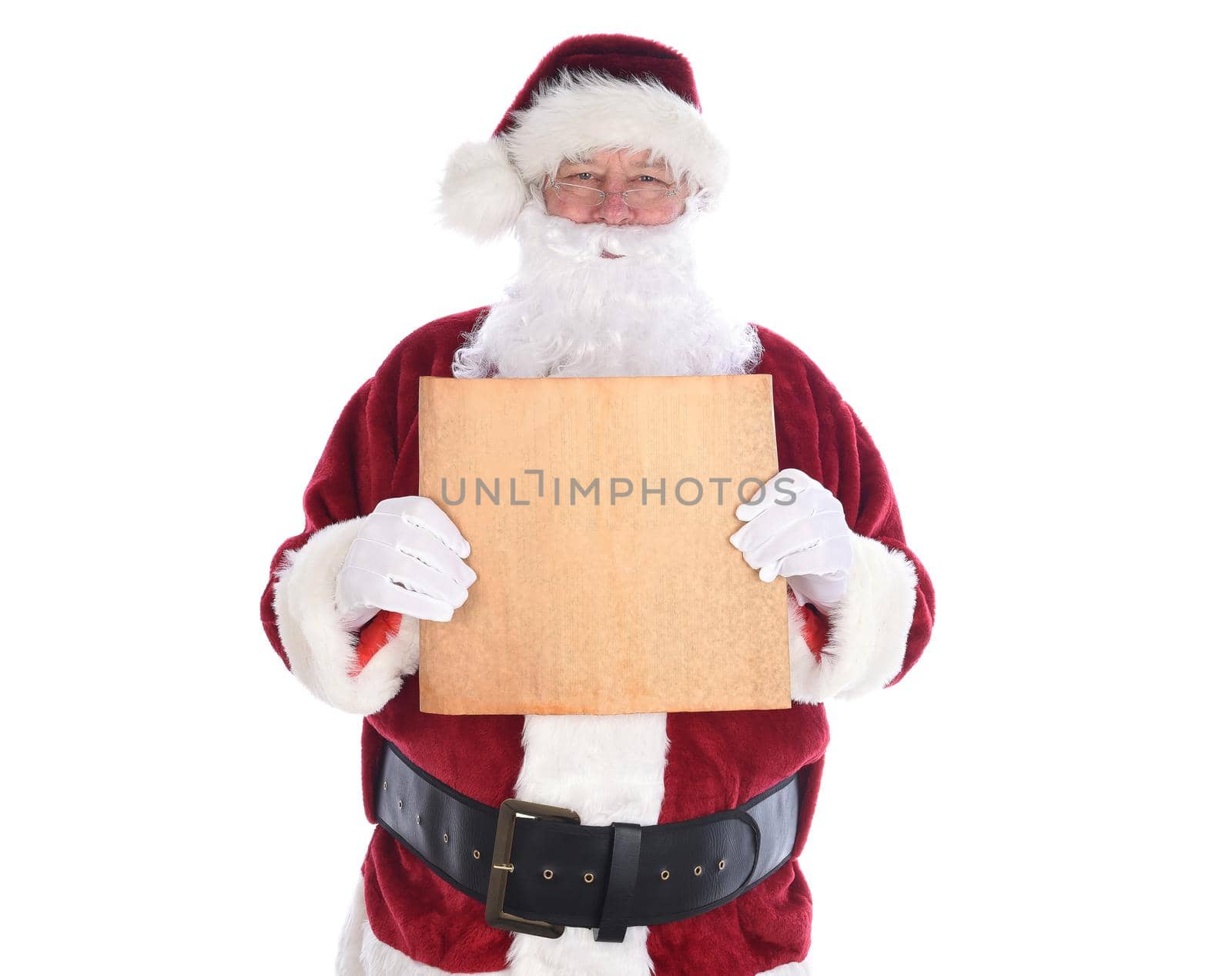 Santa Claus holding a piece old yellowed parchment paper in fornt of his torso, isolated on white. Blank paper with copy space. 