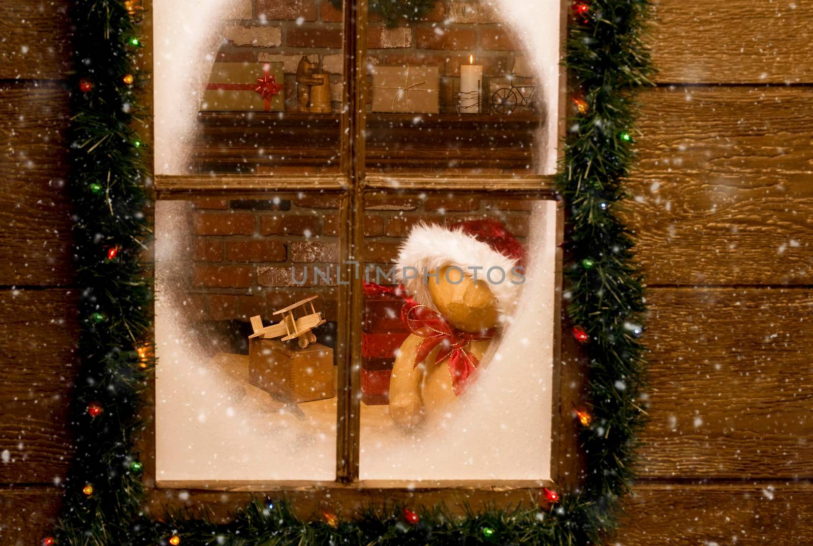 Looking through the frosty window of Santa Claus North Pole workshop with toys on work bench in front of brick fireplace. Horizontal with snow effect. by sCukrov