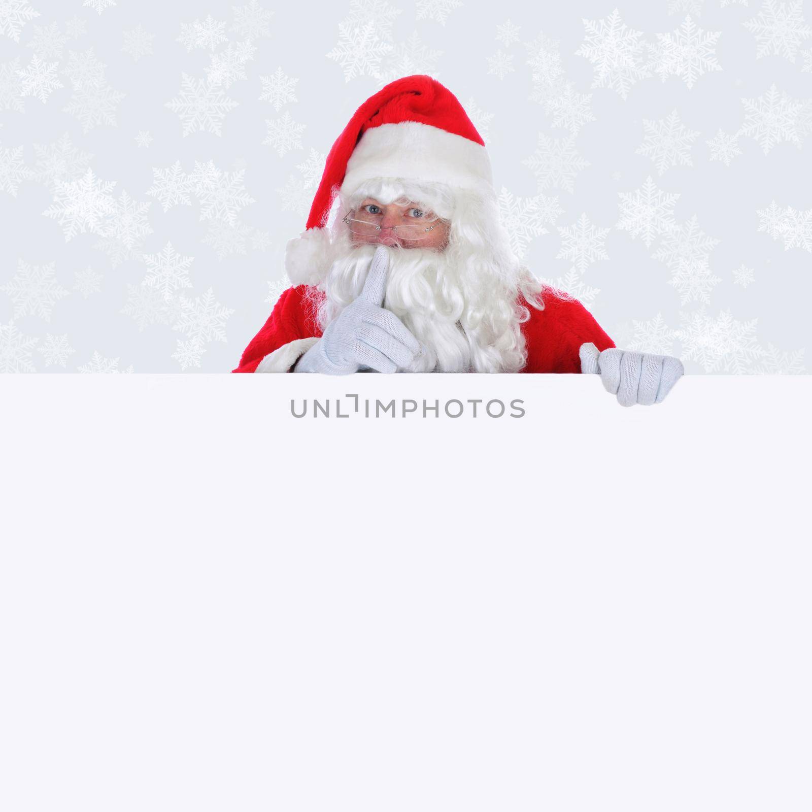 Santa Claus with blank sign making shhh sign with finger in front of face with a light silver background with snow flakes.