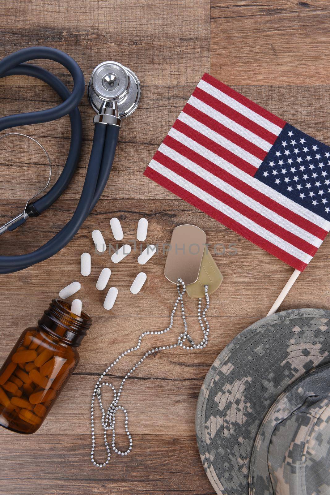 Military Health Care Concept. Dog tags, stethoscope, pills, camouflage hat and American Flag on a wood background.  by sCukrov