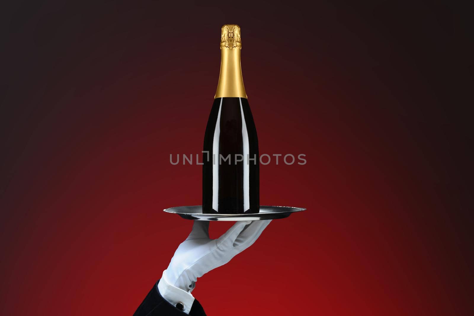 Closeup of a waiters hand and silver tray with Champagne Bottle, over red spot background. by sCukrov