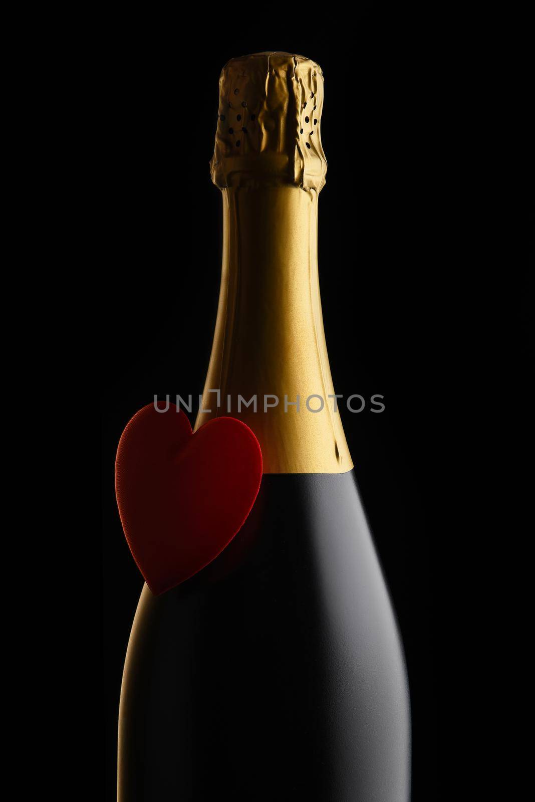  Closeup of a bottle of Champagne with a red heart against a black background by sCukrov