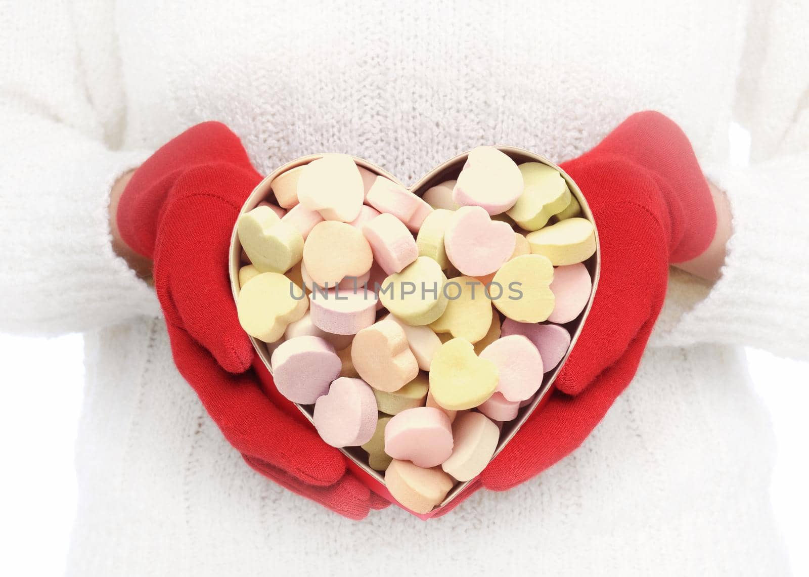 Closeup of a Valentines Day heart shaped box filled with candy hearts. Vignette added as unrecognizable woman holds the box in front of her torso.