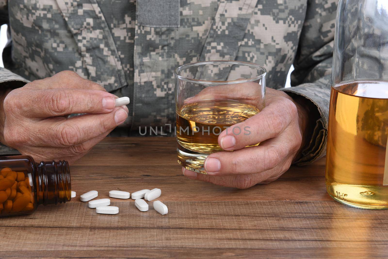 Military Drug and alcohol abuse concept. Closeup of soldier with whiskey and pills to treat his PTSD symptoms.  by sCukrov