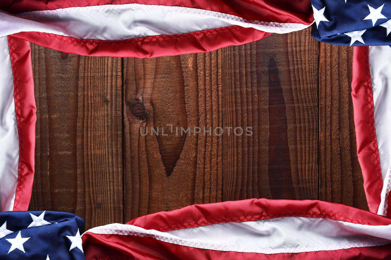 Top view of an American flagd on a dark wood table forming a frame with copy space in the middle. Horizontal format.