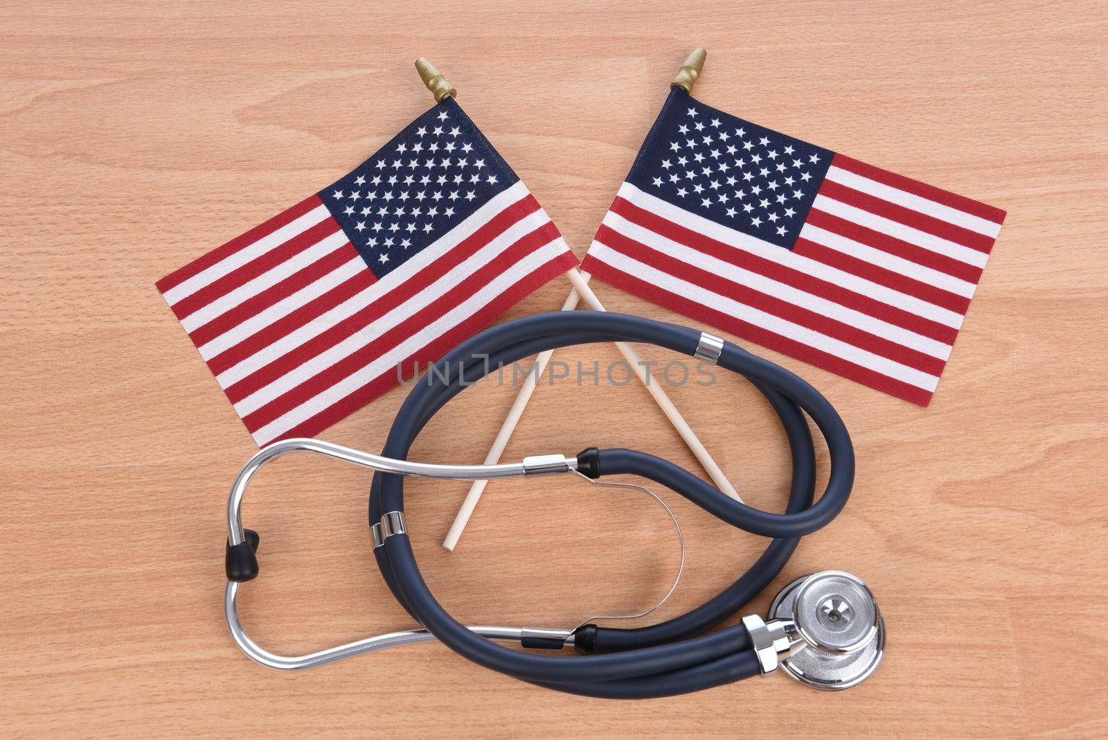 Military Health Care Concept. Light wood background with stethoscope and two crossed American flags.