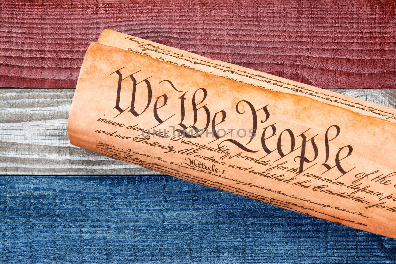 A rolled copy of the USA Constitution on red, white and blue boards background. Patriotic background for 4th of July or Memorial Day projects. by sCukrov