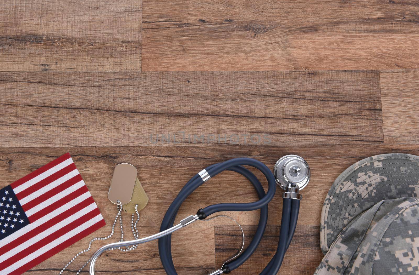 Military Health Care Concept. Camo hat, dog tags, stethoscope, pills, and American Flags on a wood background. 