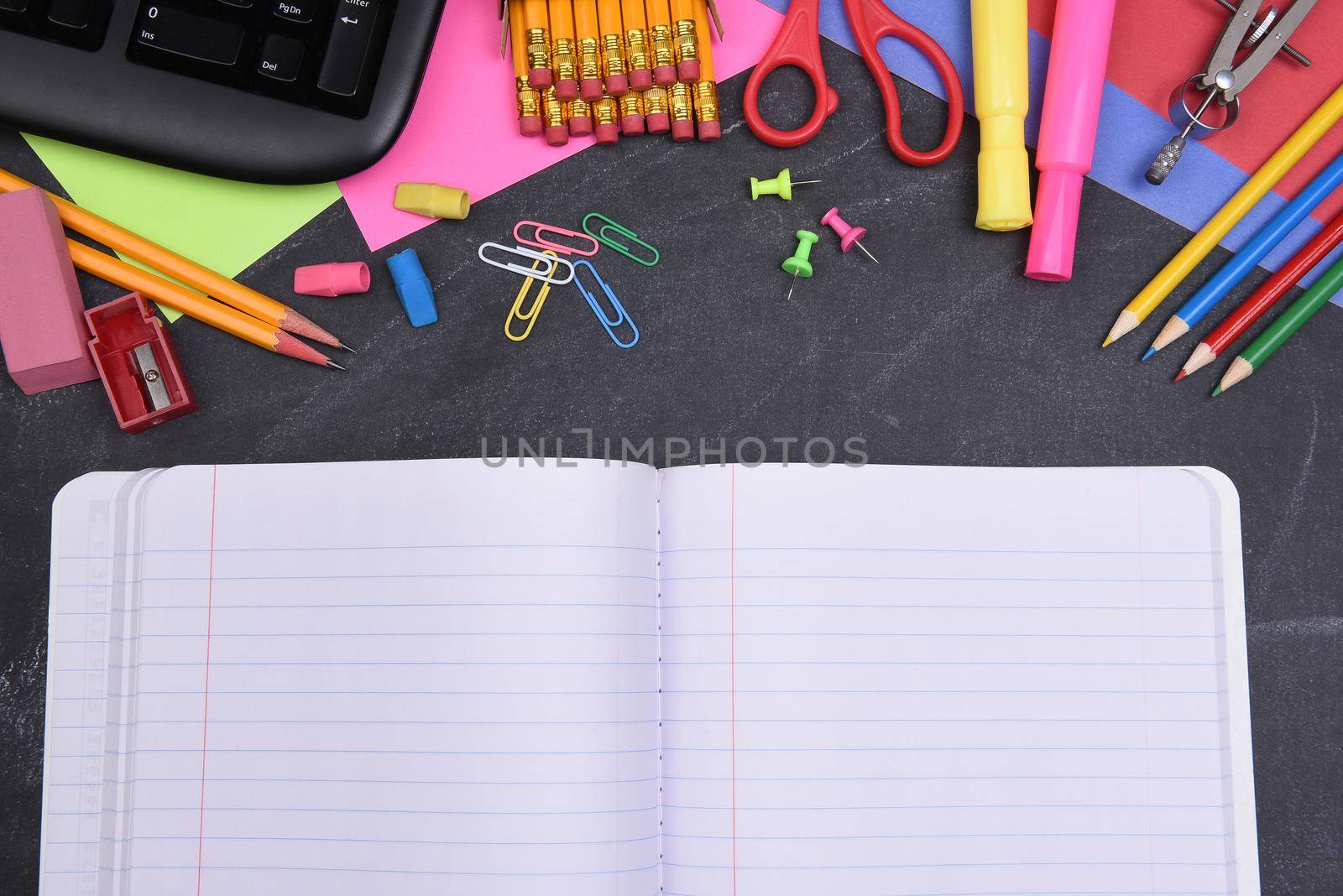 School Supplies on Chalkboard and Open Notebook by sCukrov