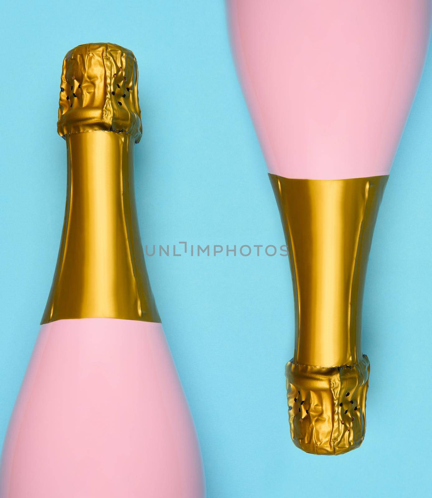 Two Pink Champagne bottles on a blue teal background. Horizontal high angle shot. by sCukrov