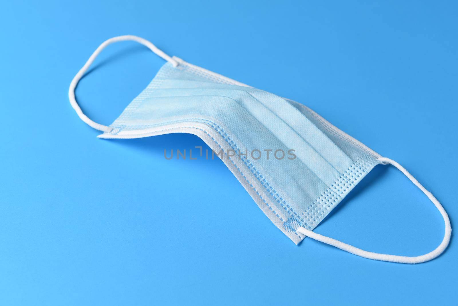 PPE Covid-19 concept. A surgical mask on a blue background. by sCukrov