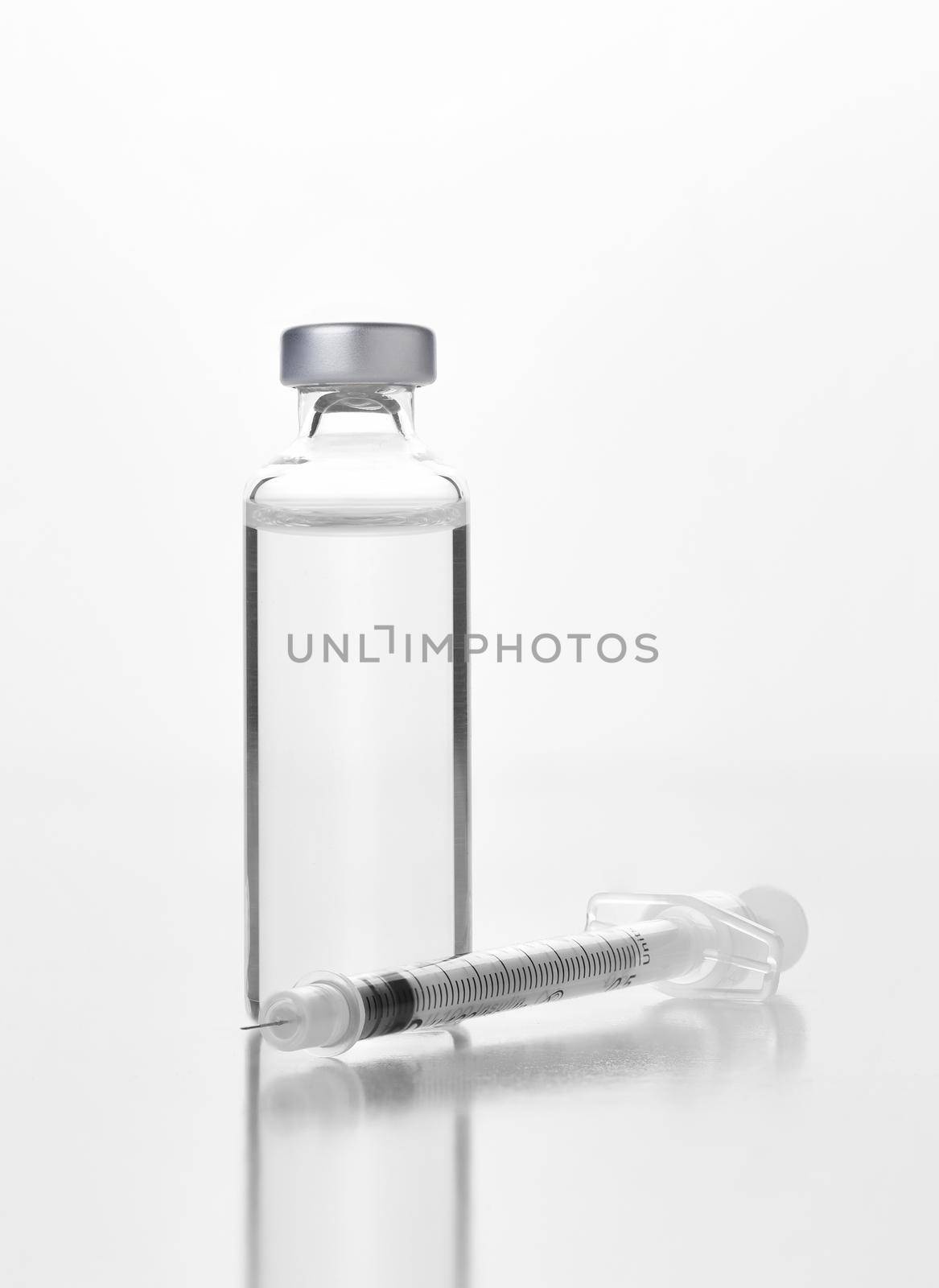 Closeup of a vial of an injectable medicine or vaccine and syringe on white. Bottle has no label.